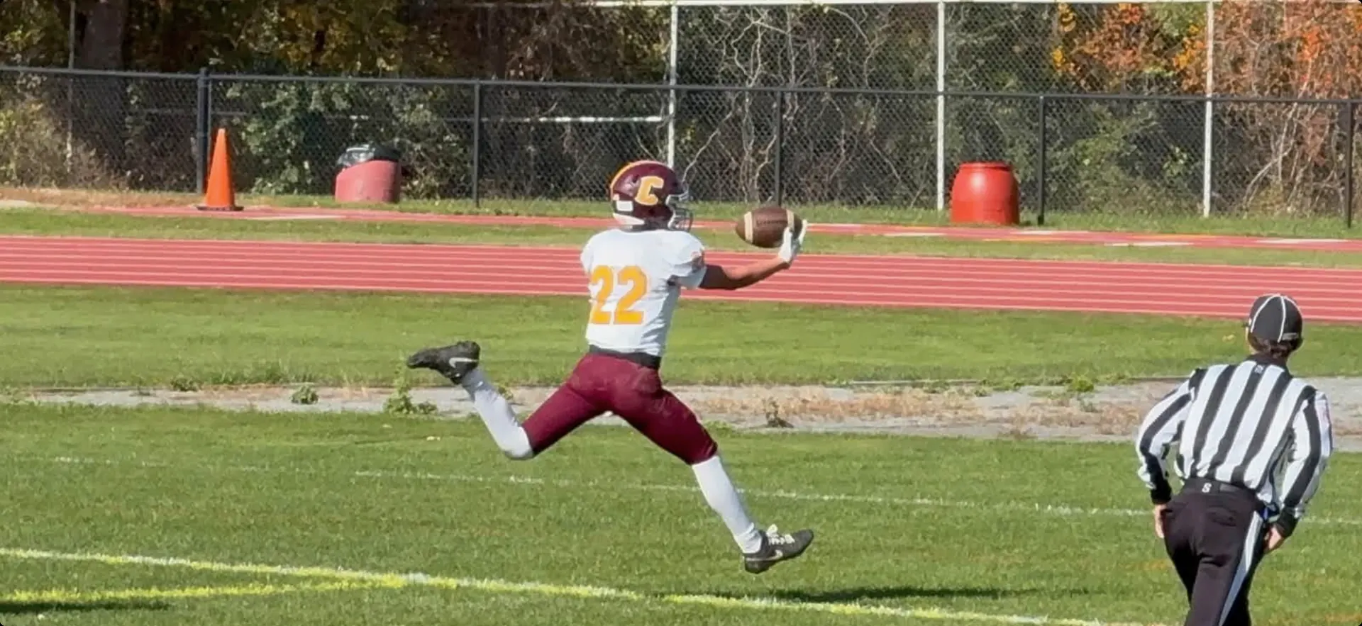 Logan Gadbois airborne in his white number 22 jersey, reaching toward a football.