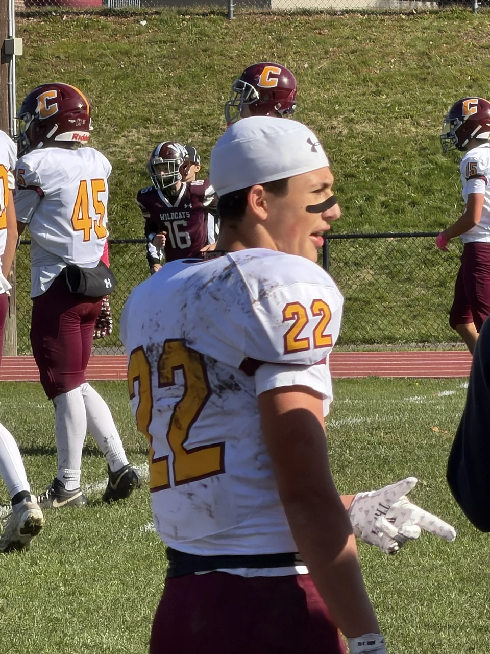 Logan wearing his white number 22 jersey and backward cap on the sideline